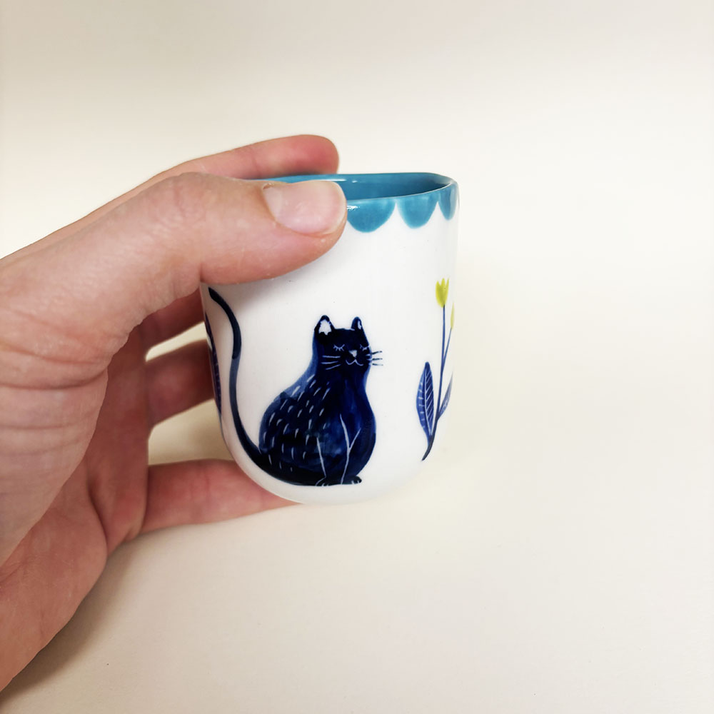 tasse en porcelaine tenue par une main.