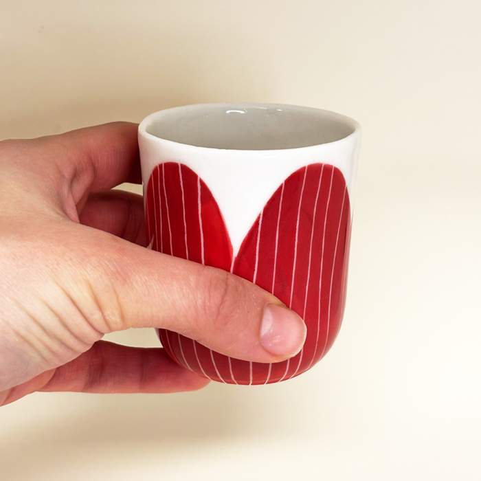main qui tien un gobelet rouge en porcelaine