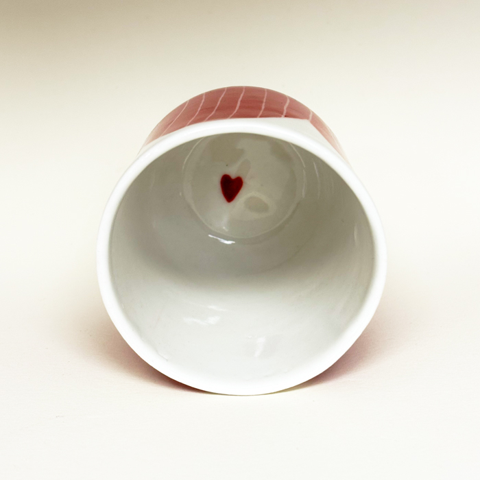 gobelet posé sur la tranche pour voir à l'intérieur.il y a un coeur rouge au fond.