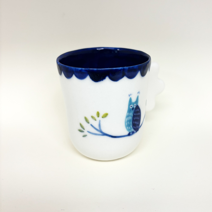 coté gauche de la tasse hibou, on voix la branche et les brindilles puis les feuilles au bout de la banche. le dessin est peint à la main, on voie la finesse du trais.