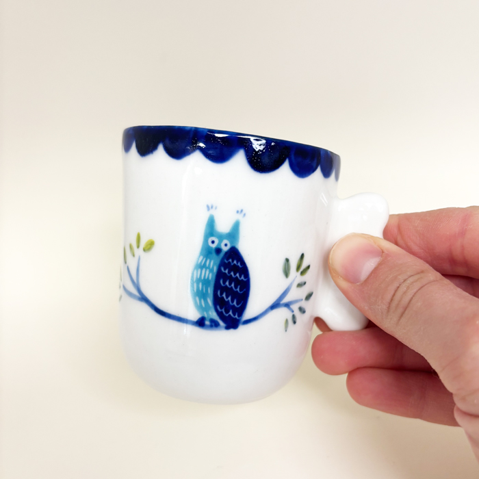 la tasse avec une main qui la tien a la anse. ce la permet de se rendre compte de la taille de la tasse et de sa prise en main