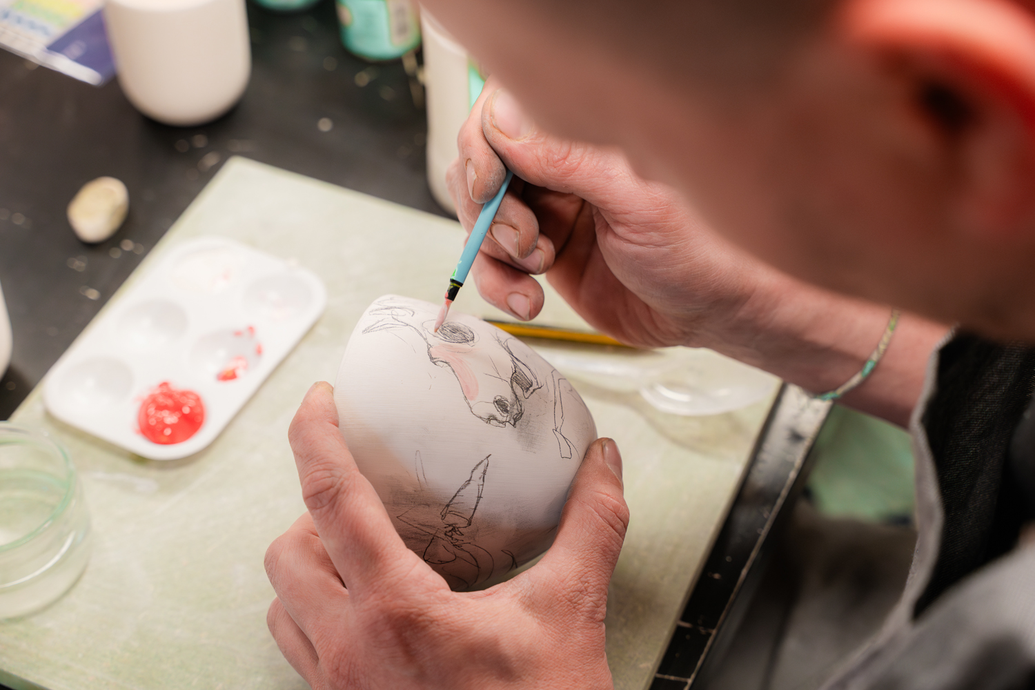 photo d'un homme qui dessine une licorne sur un bol en porcelaine